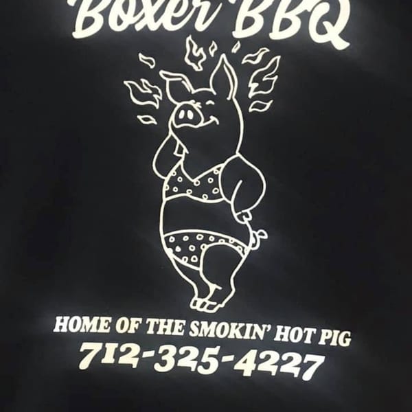 Boxer BBQ logo with a pig in a polka-dot bikini, surrounded by flames, and contact information.